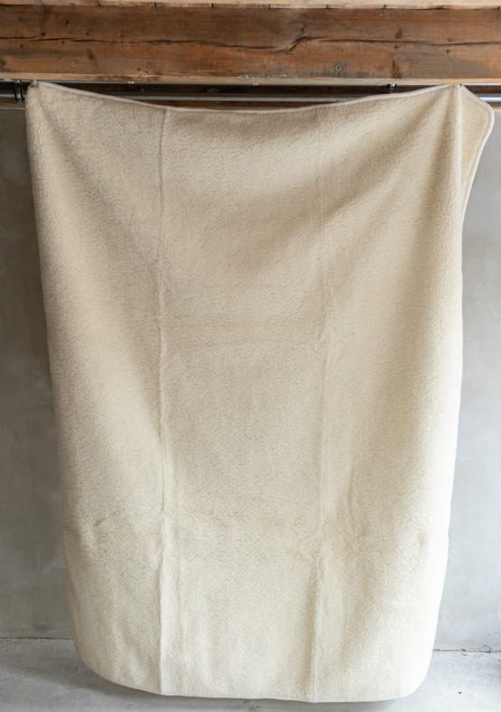 Off white schapendeken over een houten balk